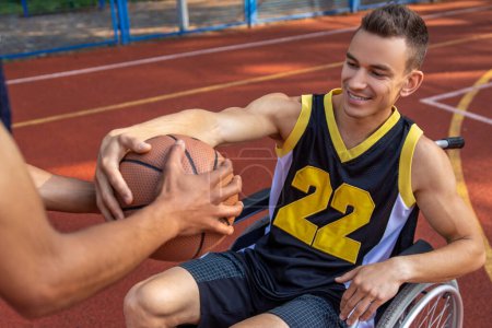 Téléchargez les photos : Joueur de basket-ball handicapé s'entraînant sur un terrain de basket extérieur - en image libre de droit