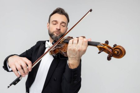 Téléchargez les photos : Violoniste élégant jouant passionnément au concert isolé sur fond gris clair - en image libre de droit