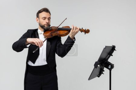 Photo for Professional violinist with notes playing classical music isolated over white background - Royalty Free Image