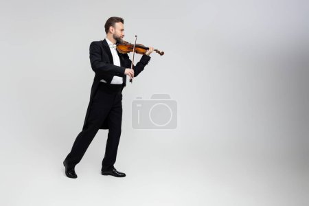 Photo for Musician man with violin performing concert isolated over light gray background, copy space - Royalty Free Image