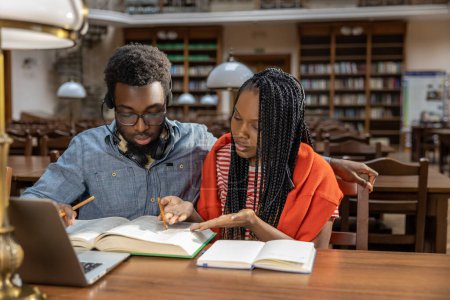 Photo for Studying together. Dark-skinned couple studying together in the library - Royalty Free Image