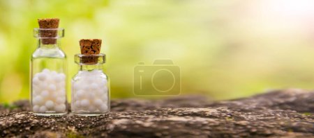 Foto de Bolas homeopáticas en botellas en el fondo de la naturaleza. Homeopatía concepto de medicina alternativa. - Imagen libre de derechos