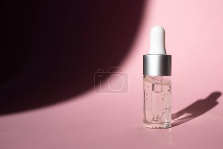 Foto de Frasco transparente de gel cosmético sobre fondo rosa. Vista lateral, espacio para texto. - Imagen libre de derechos