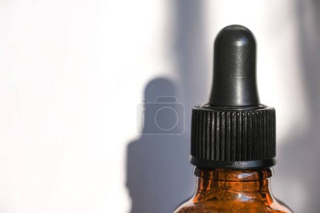 Photo for Liquid emulsion in a dark glass bottle with a dispenser. Serum with collagen and peptides, product advertisement. - Royalty Free Image