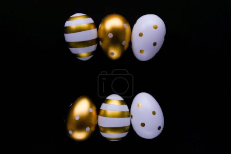 Foto de Huevos de Pascua dorados en fila sobre un fondo negro. Concepto festivo de Pascua. Estilo plano, espacio para texto. - Imagen libre de derechos