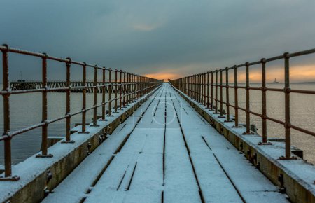 Foto de Una mañana helada y nevada en la playa de Blyth en el antiguo muelle de madera que se extiende hasta el Mar del Norte - Imagen libre de derechos