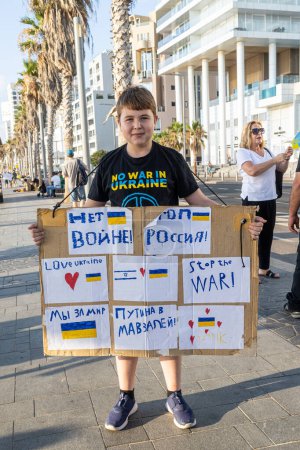 Foto de Tel Aviv, Israel - 20 de marzo de 2022, Protesta contra la agresión rusa en Ucrania. El niño sostiene un cartel: ¡Alto a la guerra! Putin al mausoleo! - Imagen libre de derechos