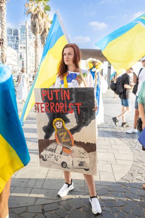 Foto de Tel Aviv, Israel - 20 de marzo de 2022, Protesta contra la agresión rusa en Ucrania. Una niña en traje nacional ucraniano sostiene un cartel con la inscripción: Putin es un terrorista - Imagen libre de derechos