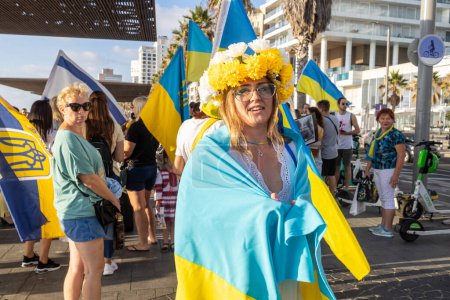 Foto de Tel Aviv, Israel - 20 de marzo de 2022, Protesta contra la agresión rusa en Ucrania. Una niña en una corona amarilla envuelta en la bandera ucraniana en un mitin. - Imagen libre de derechos