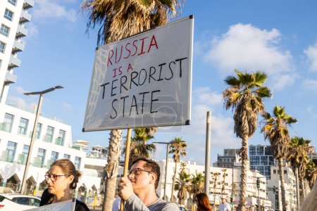 Téléchargez les photos : Tel Aviv, Israël - 20 mars 2022, Manifestation contre l'agression russe en Ukraine. Un homme et une femme avec une affiche - La Russie est un État terroriste. Aujourd'hui, la Russie a bombardé Vinnitsa - en image libre de droit