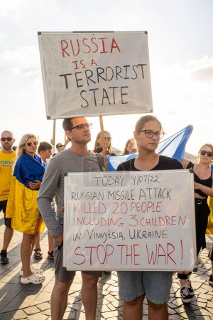 Téléchargez les photos : Tel Aviv, Israël - 20 mars 2022, Manifestation contre l'agression russe en Ukraine. Un homme et une femme avec une affiche - La Russie est un État terroriste. Aujourd'hui, la Russie a bombardé Vinnitsa - en image libre de droit