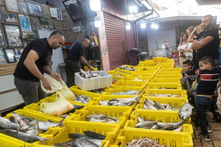 Acre, Israel - 01. November 2022, Fischmarkt an einem freien Tag. Verschiedene Arten von frischem Fisch in Boxen mit Eis. Verkäufer verkaufen an Käufer