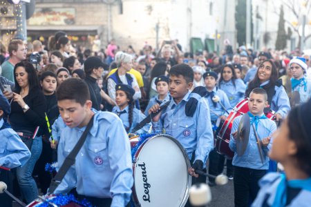 Téléchargez les photos : Haïfa, Israël - 17 décembre 2022 : Les élèves de l "école épiscopale Saint-Élie participent au défilé de Noël dans la colonie allemande. Les spectateurs regardent le défilé - en image libre de droit