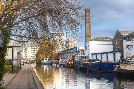 Foto de Londres, Reino Unido - 10 de diciembre de 2022, Paisaje escénico del Regent 's Canal urbano en Londres, Inglaterra, con botes de canal largos a la antigua y arquitectura urbana moderna - Imagen libre de derechos