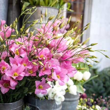 Foto de Ramo de flores de eustoma rosa o lisianthus en una cesta grande para la venta en la entrada de la tienda como decoración - Imagen libre de derechos