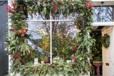 Photo for Shop window decorated around the perimeter with fir branches with red berries of St. John's wort and pine cones - Royalty Free Image