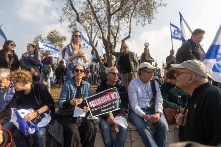 Téléchargez les photos : JERUSALEM, ISRAEL - February 20 2023: Israelis protest near the Knesset against plans by prime minister Benjamin Netanyahu new government to trample the legal. People with flags sit on the steps - en image libre de droit