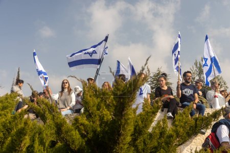 Foto de JERUSALEM, ISRAEL - 20 de febrero de 2023: Los israelíes protestan cerca de la Knesset contra los planes del primer ministro Benjamin Netanyahu de pisotear la ley. La gente con banderas se sienta en la valla - Imagen libre de derechos