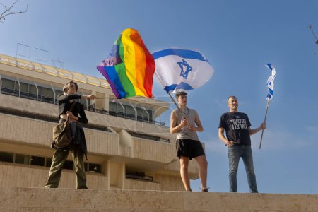 Foto de JERUSALEM, ISRAEL - 20 de febrero de 2023: Protesta israelí cerca de la Knesset contra los planes del primer ministro Benjamin Netanyahu. Una chica con una bandera LGBT, un joven con una bandera israelí - Imagen libre de derechos