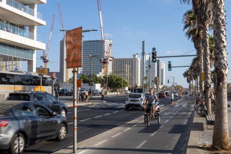 Foto de Tel-Aviv, Israel - 20.07.2022, skyline and sand beaches of Tel Aviv city on sunset. Men ride bikes along the bike path along the beach. - Imagen libre de derechos