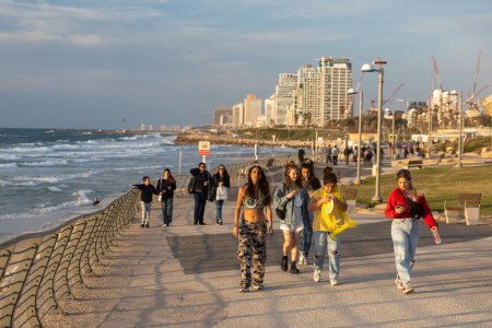 Foto de Tel Aviv Israel - 07 de marzo de 2023, Cuatro adolescentes caminan a lo largo del paseo marítimo en la víspera de Purim. - Imagen libre de derechos