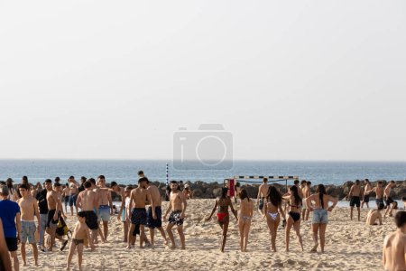 Foto de Haifa, Israel 12 marzo 2023, Los jóvenes en Dado Beach tomar el sol, jugar al bádminton, voleibol, nadar. Hora de verano. - Imagen libre de derechos