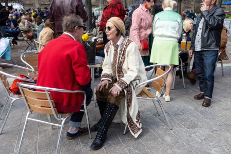Photo for London UK - April 15 2023: Classic Car Boot Sale by Vintage. Retro festival. People sell vintage clothing, jewellery, homeware on their classic vehicles. Man and woman in red at table in street cafe - Royalty Free Image