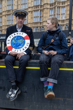 Téléchargez les photos : Londres, R.-U. 22.04.2023, The Big One Demonstration. Un homme en uniforme naval et une casquette de capitaine tiennent une bouée de sauvetage avec l'inscription - SS Planet - Titanic - en image libre de droit