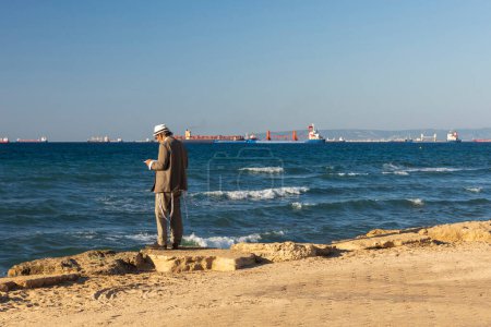 Photo for Haifa, Israel - September 27, 2023, An Orthodox man wearing a knitted kippah reads a prayer on the Jewish New Year Rosh Hashanah on the shores of the Mediterranean Sea. - Royalty Free Image