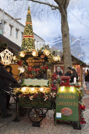 Téléchargez les photos : Lire Royaume-Uni, - 22, décembre 2023, marché de Noël. Les gens achètent des châtaignes rôties chaudes. Arbre de Noël décoré, ambiance festive. - en image libre de droit