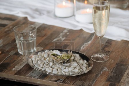 Plat d'huîtres élégant avec champagne et eau sur table rustique
