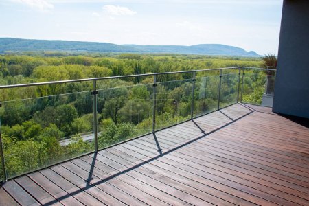 Wohnung Balkon Blick auf die Landschaft mit exotischen gerillten Cumaru-Holzbelag und modernes Glasgeländer