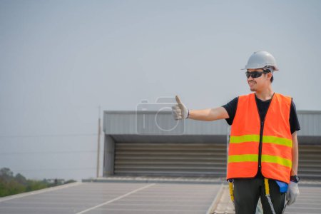 Photo for Asian engineers wearing protective vest and white hardhat standing thumb ups and looking to the copy space while holding tablet. - Royalty Free Image