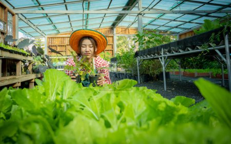 Photo for Beautiful asian female farmer holding a pot of vegetables while eyes close. - Royalty Free Image