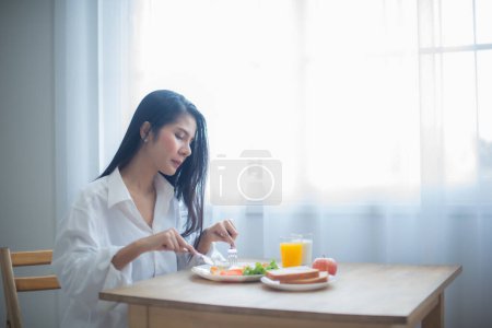 Foto de Hermosa mujer asiática le encantó la sensación de masticar los huevos fritos crujientes y el crujido de las verduras frescas en su boca. - Imagen libre de derechos