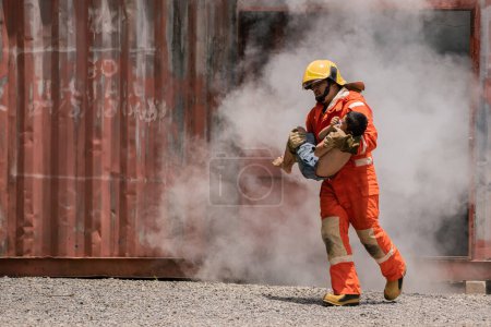 Photo for The firefighter is holding the child tightly to his chest as he rushes out of the building with smoke. - Royalty Free Image
