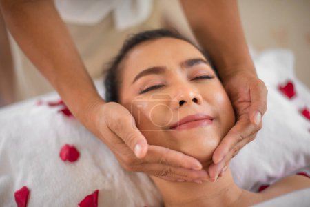 Photo for The skilled masseuse's gentle hands glided over the beautiful asian woman's chin with precision and expertise releasing tension and promoting a sense of deep relaxation. - Royalty Free Image