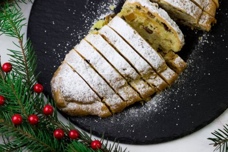 Téléchargez les photos : Vue de dessus à travers les branches de l'arbre de Noël sur l'enflure. cupcake allemand classique sur une plaque noire - en image libre de droit