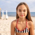 Close up of Little cute child girl in on the beach with smile on summer vacation. Happy children kid enjoy and fun outdoor activity lifestyle