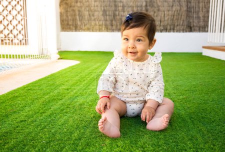 Photo for Adorable little baby girl with cute smile sitting unsupported and starting to take first crawling steps on her own, being independent - Royalty Free Image