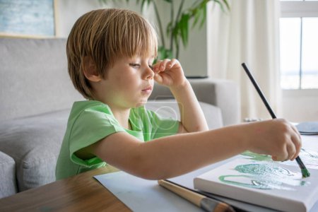Foto de Lindo niño pintando con un pincel en la sala de estar. - Imagen libre de derechos