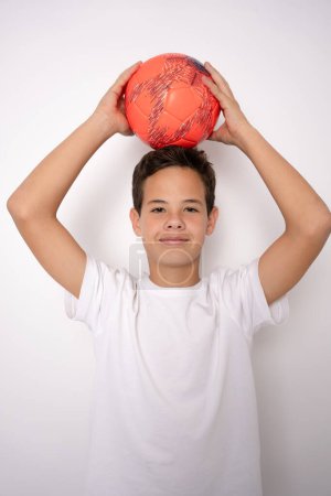 Téléchargez les photos : Photo d'un adolescent en tenue de sport tenant un ballon de football - posant en studio - en image libre de droit