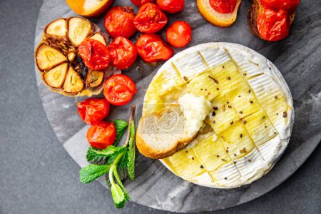 baked cheese Brie or Camembert with tomato, garlic and herbs healthy meal food snack on the table copy space food background rustic top view