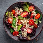 Quinoa salad tomato, green lettuce mix healthy meal food snack on the table copy space food background rustic top view keto or paleo diet veggie vegan or vegetarian food