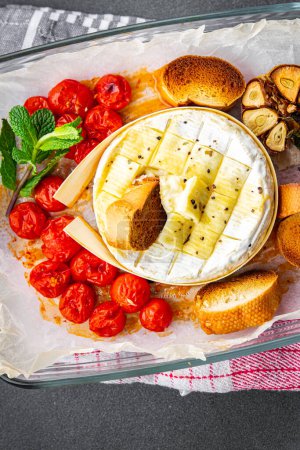 baked soft cheese Brie or Camembert tomato, garlic and herbs meal food snack on the table copy space food background rustic top view