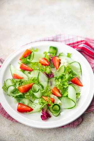 Salatgurke, Erdbeere, Salat gesunde Mahlzeit Snack auf dem Tisch kopieren Weltraum Lebensmittel Hintergrund rustikale Draufsicht Keto oder Paläo-Diät veggie vegan oder vegetarisches Essen