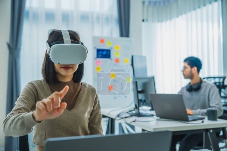 Téléchargez les photos : Asian and Indian developer program coding sent to virtual reality headset to implement ai project at office - en image libre de droit