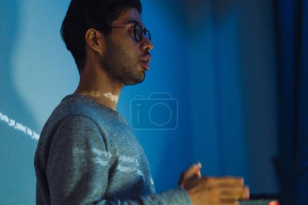 Foto de Hombre indio desarrollador presentación acerca de la codificación de datos de software con devops equipo en la noche en la oficina - Imagen libre de derechos