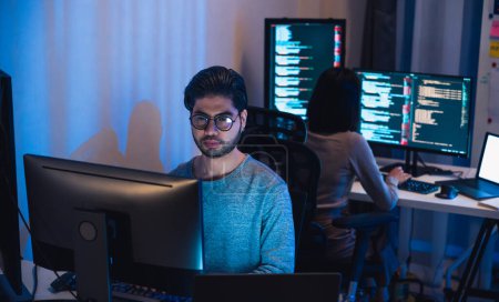 Téléchargez les photos : Asiatique et indien développeur devops équipe de travail sur le codage promgram avec logiciel ordinateur la nuit dans bureau - en image libre de droit