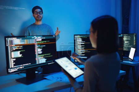 Foto de Hombre indio desarrollador presentación acerca de la codificación de datos de software con devops equipo en la noche en la oficina - Imagen libre de derechos